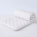 White quilted Xbound waterproof mattress protector shown half rolled on a clean studio background