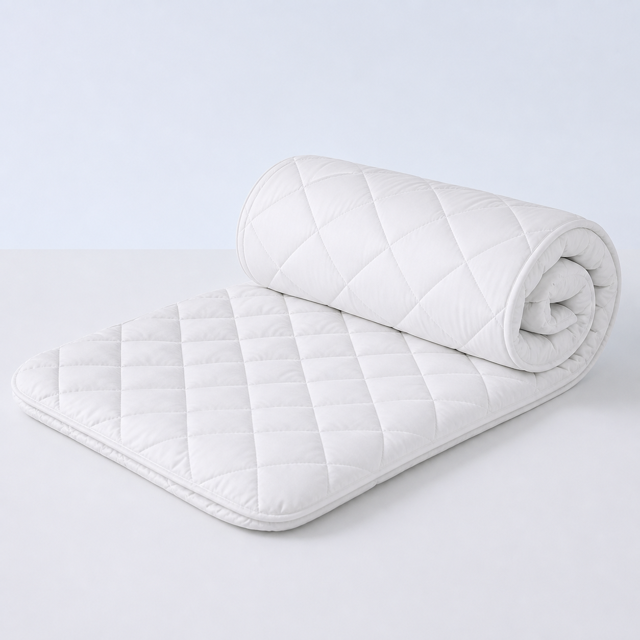 White quilted Xbound waterproof mattress protector shown half rolled on a clean studio background
